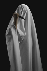 Midsection of man holding umbrella standing against black background