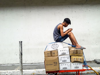 Full length of man sitting against wall