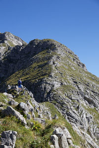 Low angle view of man climbing mountain against clear sky