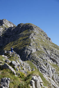 Tourists on mountain against blue sky