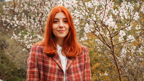 Happy red-haired girl under spring flower tree. spring mood.