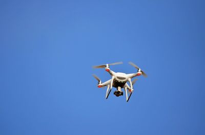 Low angle view of airplane flying against clear blue sky