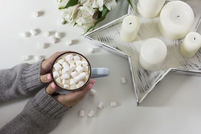 Cropped image of hands holding drink with marshmallow on table