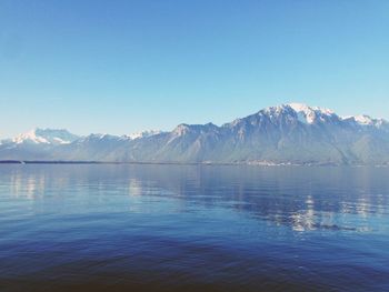 Scenic view of lake and mountains against clear blue sky