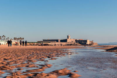 People on beach against clear sky