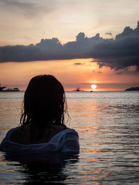 Rear view of woman looking at sea during sunset