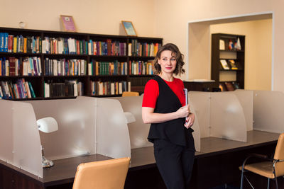 Professional woman educator or manager posing at public library of high school or college