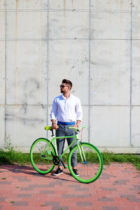 Portrait of man riding bicycle on sidewalk in city