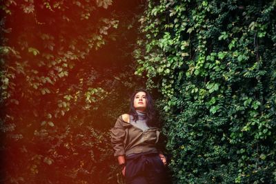 Woman looking away while standing by plants