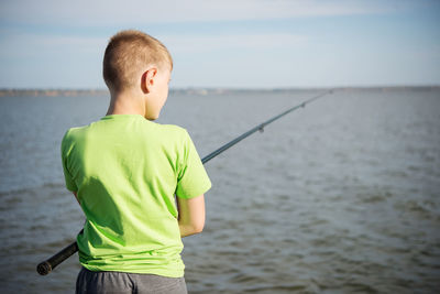 Rear view of boy looking at sea against sky