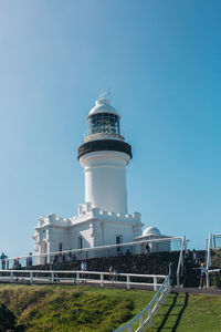 Lighthouse by buildings against clear sky