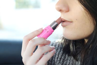 Close-up midsection of woman applying lipstick