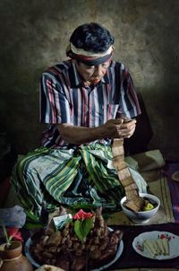 High angle view of male vendor reading text while selling food at night