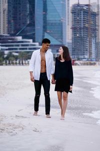 Young diverse couple walking on the beach holding hands