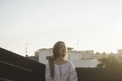 Beautiful woman with eyes closed sitting against sky