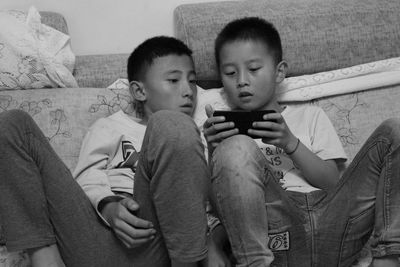 Brothers using mobile phone while sitting at home