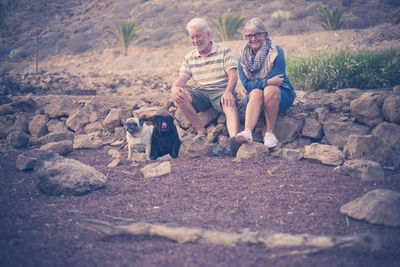 Rear view of woman with dog sitting on rock