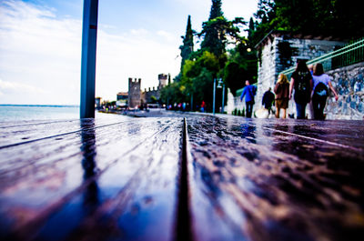 People on sidewalk in city against sky