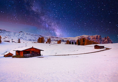 Houses on snow covered landscape against sky at night