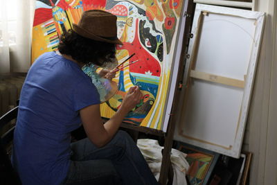 Woman painting while sitting at art studio