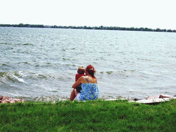 Rear view of friends on beach against sea