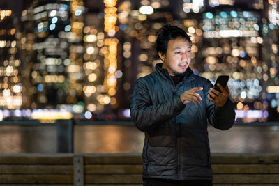 Asian man wearing overcoat suit using smart mobile phone 