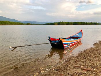 Boat moored on shore against sky