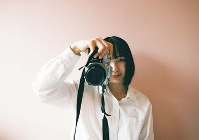 Portrait of man photographing against white background