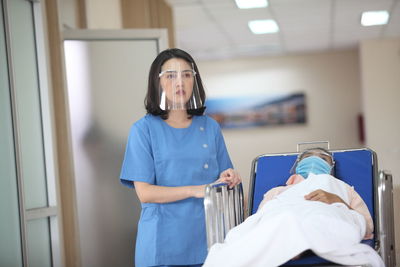 Doctor wearing face shield while standing by patient at hospital