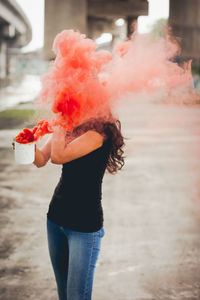 Woman holding mug emitting red smoke on road