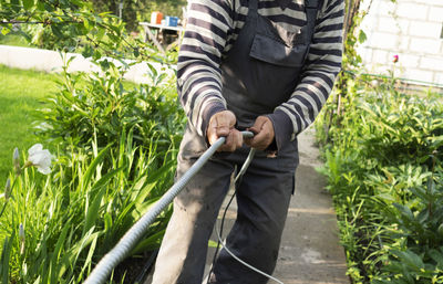 Adult caucasian male pulls cable through metal protective sleeve.