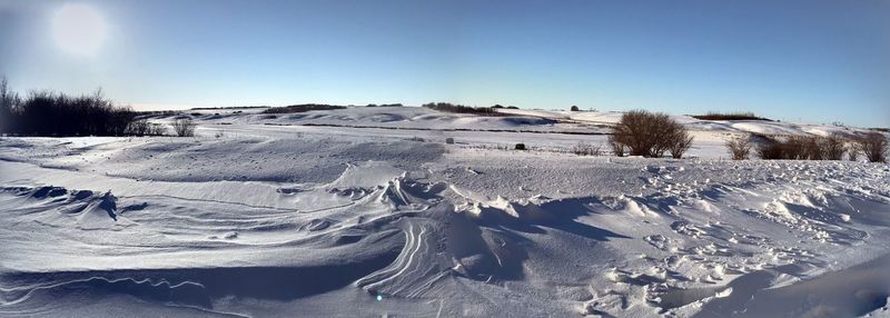 Snow covered land against clear sky