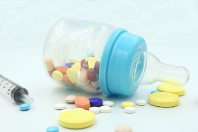 Close-up of medicines in baby bottle with syringe on blue background