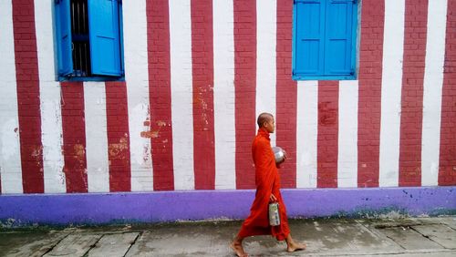 Full length of monk walking against building