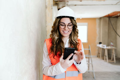 Professional architect woman in construction site using mobile phone and blueprints.home renovation