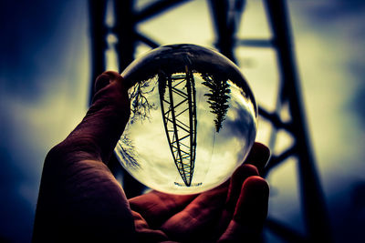 Close-up of hand holding crystal ball against blurred background