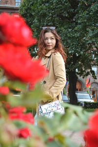 Young woman standing by flowering plants in city