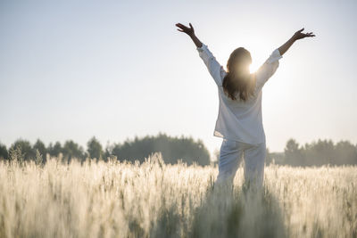 Woman with arms raised standing in cornfield