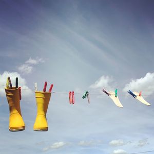 Low angle view of shoes hanging on clothesline against sky during sunny day