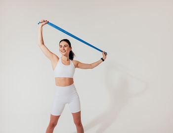 Portrait of young woman exercising against white background