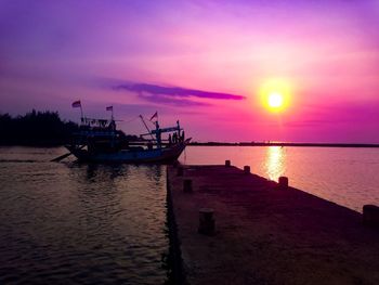 Fishing boat moored in sea against sky during sunset