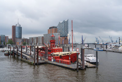 Boats in river by buildings against sky in city