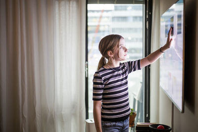 Girl touching digital display of television set at modern home