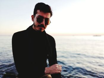 Portrait of man wearing sunglasses sitting against sea