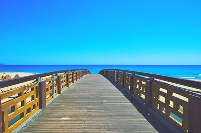 Pier over sea against clear blue sky