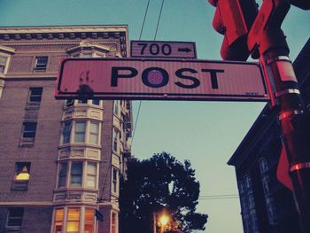 Low angle view of road sign against sky in city