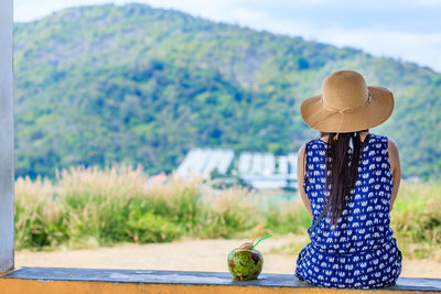 Rear view of woman wearing hat against lake