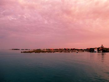 Scenic view of sea by buildings against sky during sunset