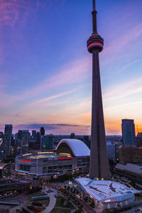 Communications tower in city against sky during sunset