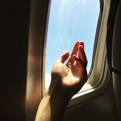 Cropped image of hand against airplane window